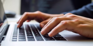 Hands typing code on a laptop keyboard.